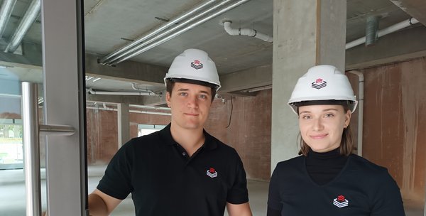 Zwei Mitarbeiter auf einer Baustelle mit Schutzhelm