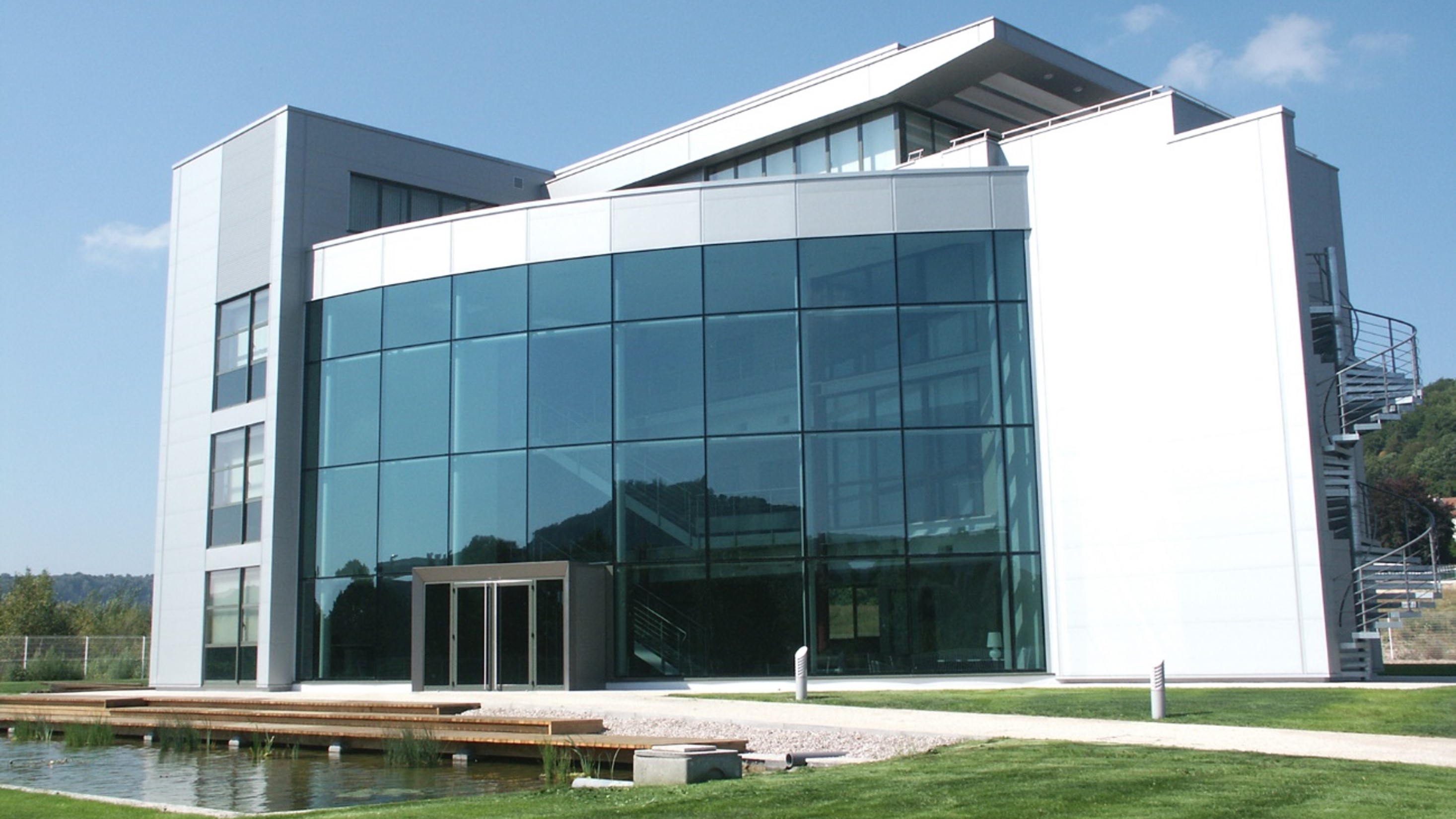 Bürogebäude mit Glasfront und kleinem Teich vor dem Eingang